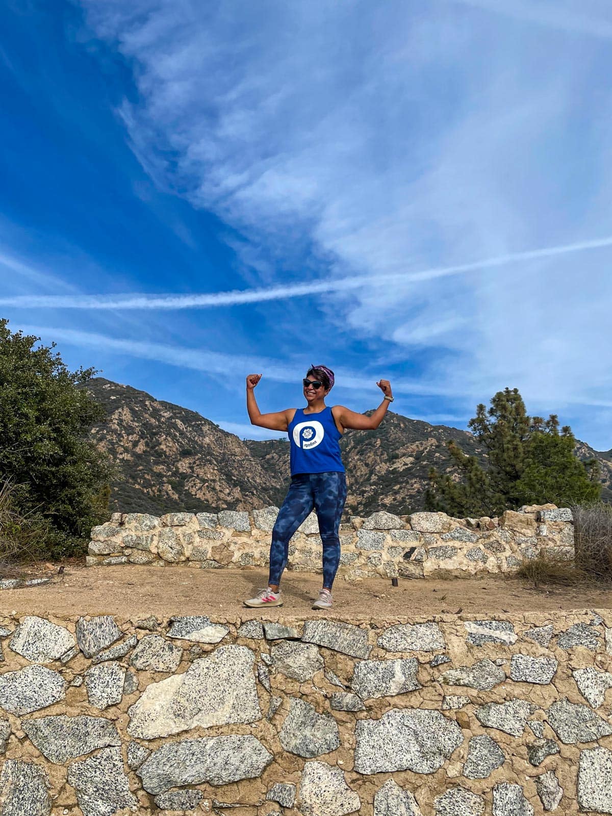 strong person posing on a trail with hands in the air