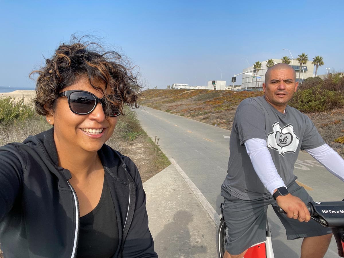 couple biking along the beach and smiling