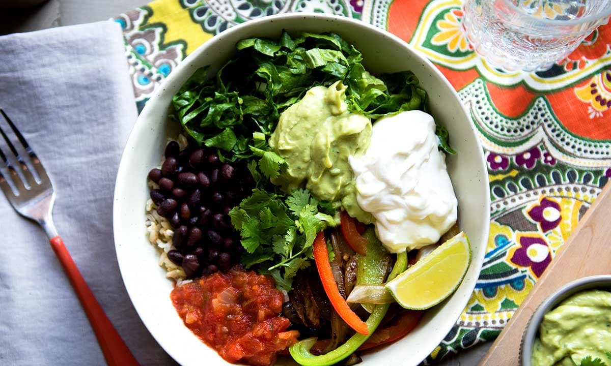 homemade chipotle bowl including avocado crema, cashew cream, lime, bell peppers, black beans, salsa and lettuce.