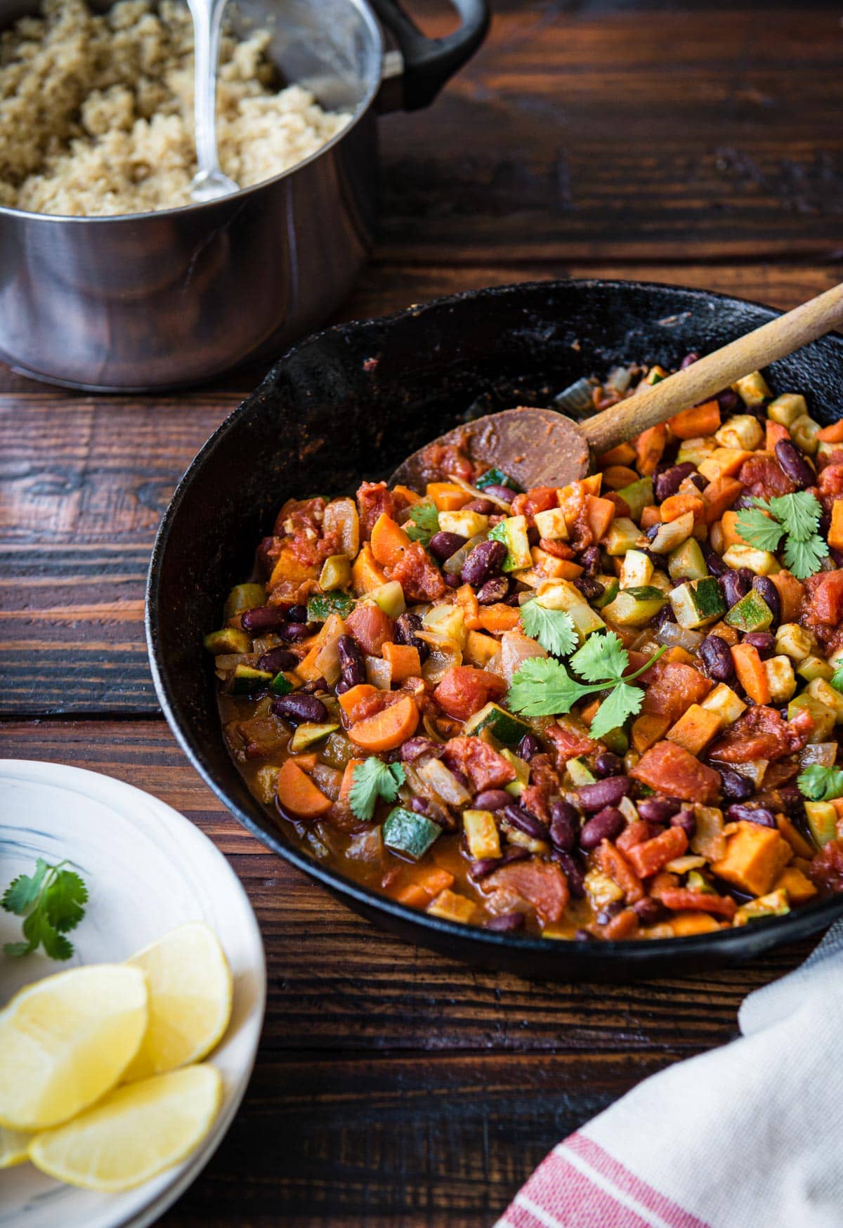 black skillet full of a plant-based chili recipe with a wooden spoon.