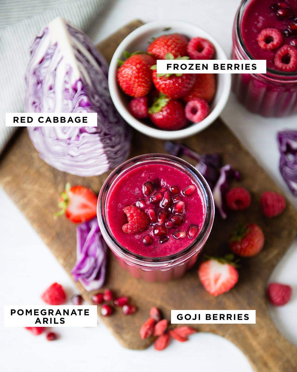 labeled ingredients for a red fruit smoothie including frozen berries, red cabbage, pomegranate arils and goji berries.