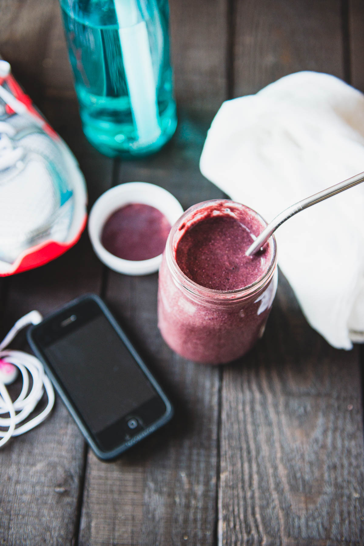 purple post workout smoothie in a glass jar with a metal straw.