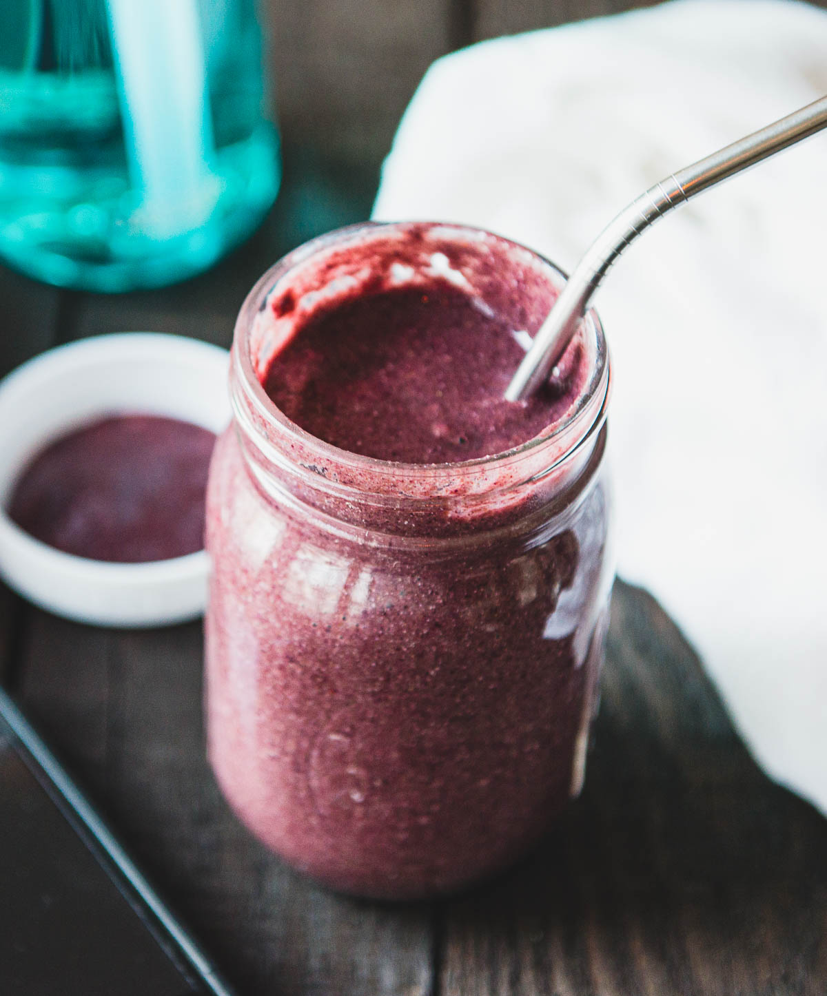 purple smoothie in a glass jar with a metal straw.