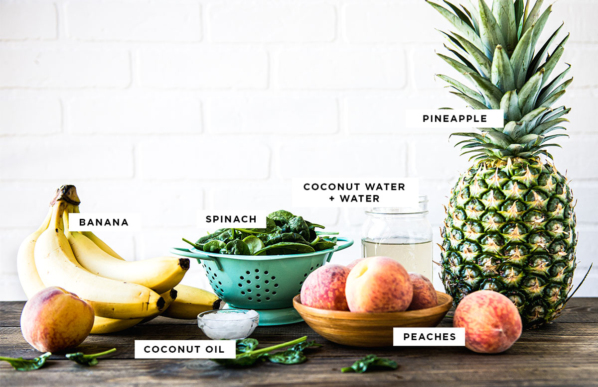 Labeled ingredients for a pre-workout smoothie, including banana, coconut oil, spinach, peaches, coconut water, and pineapple, ideal smoothie for energy. 