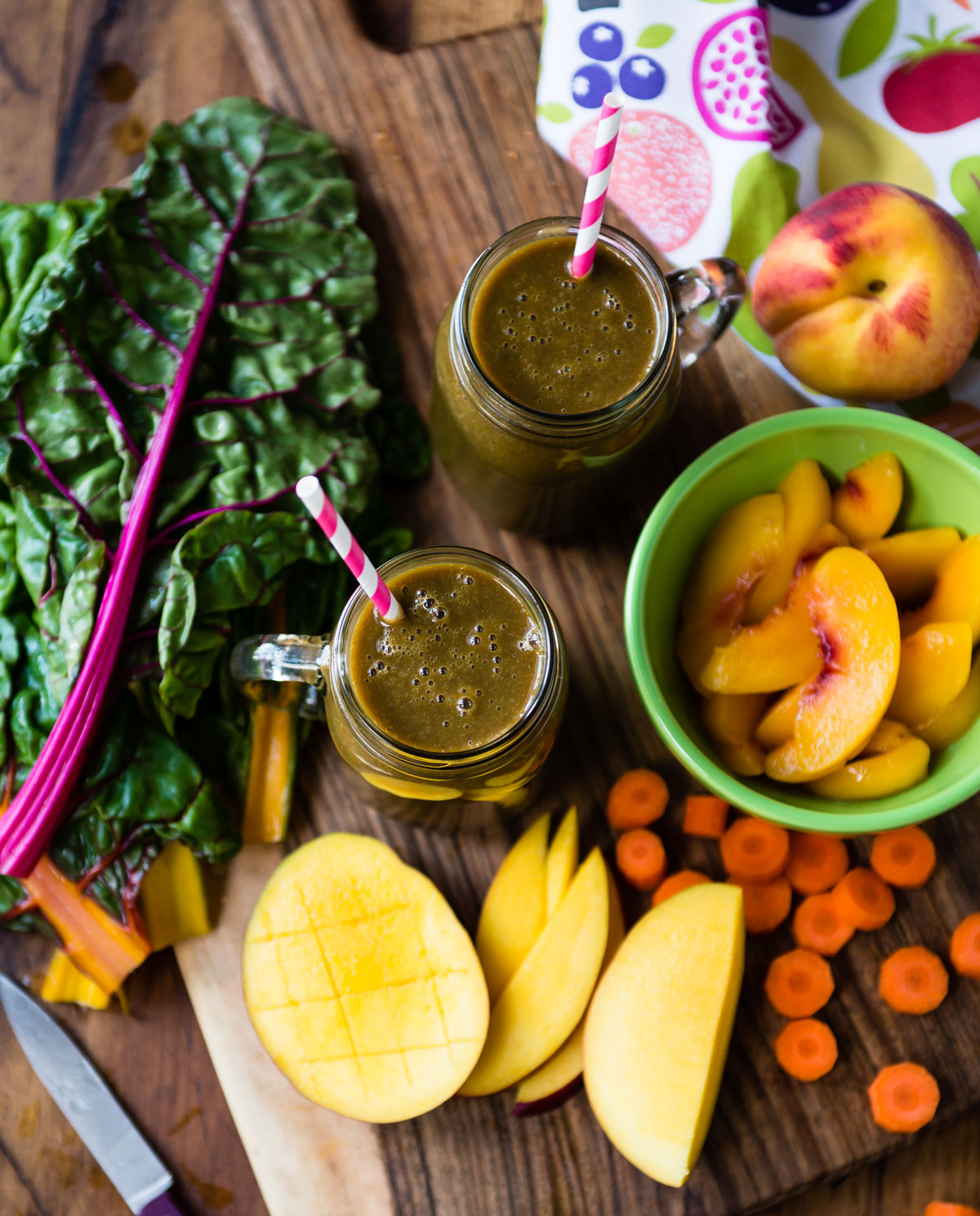 Serving pregnancy smoothies on table with chopped fruit and vegetables.