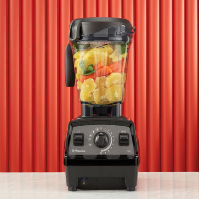 Vitamix Propel 750 blender on counter with carrots, oranges and mint.
