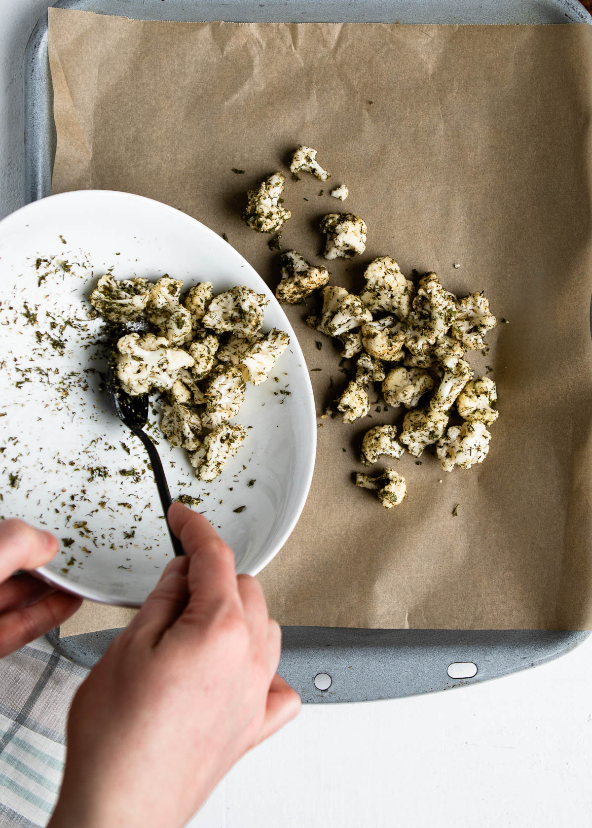 scooping ranch cauliflower onto a baking sheet lined with parchment paper.