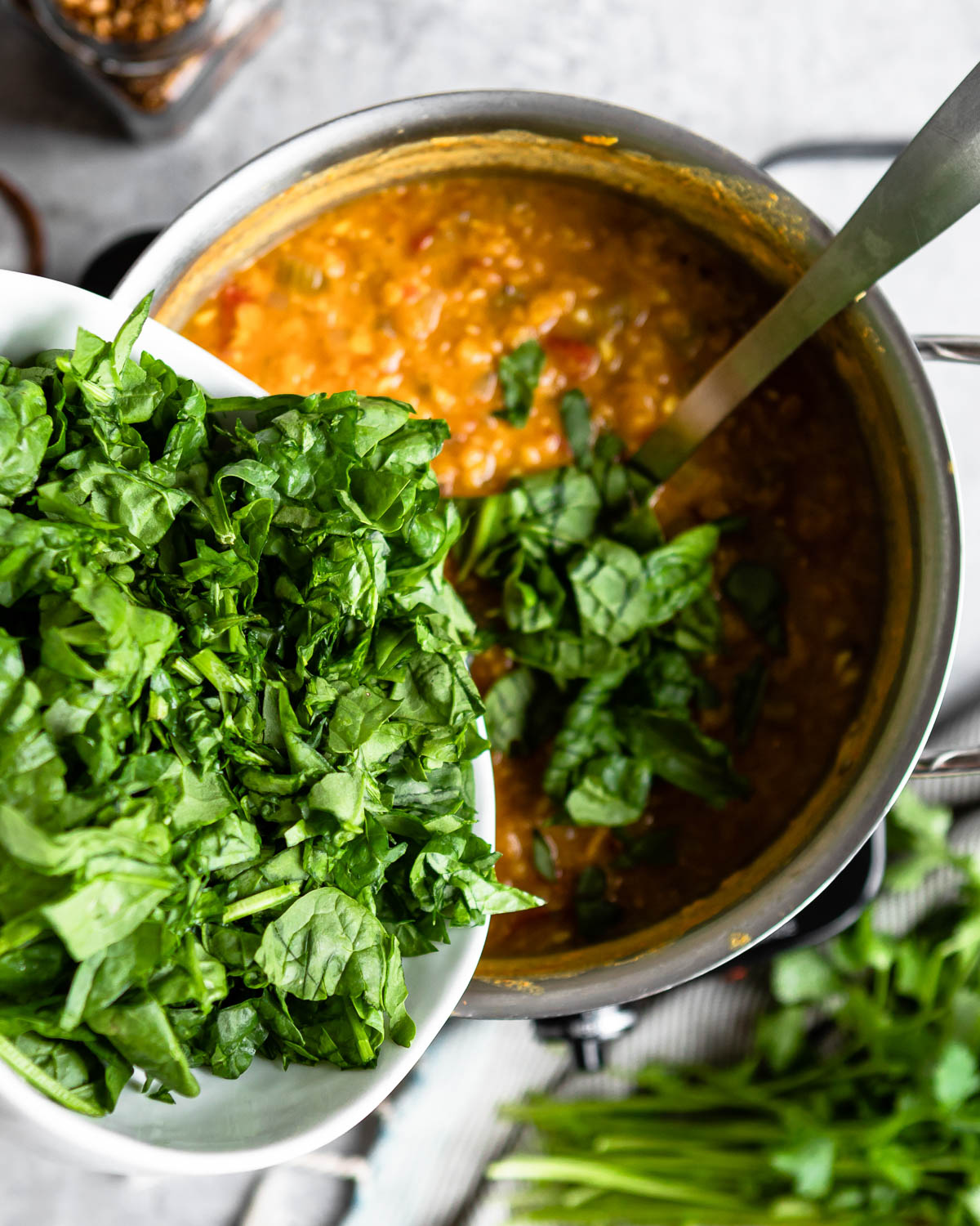 Adding fresh spinach into a pot of soup