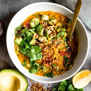 overhead photo of red lentil soup topped with avocado