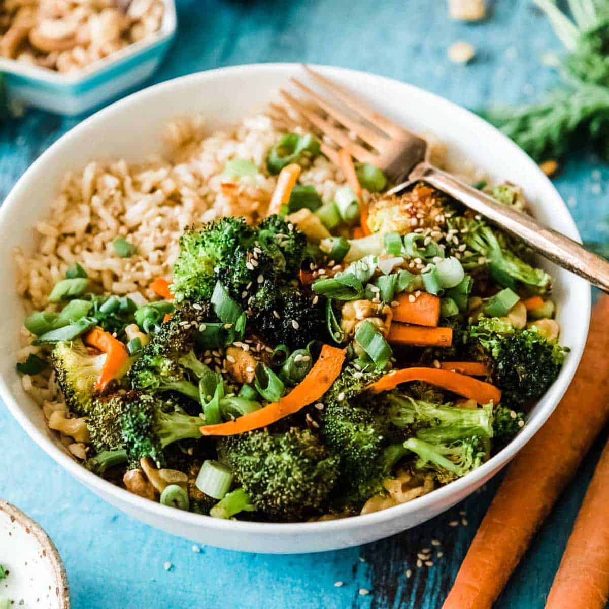 rice bowl recipe with broccoli and carrots in a white bowl with a gold fork.