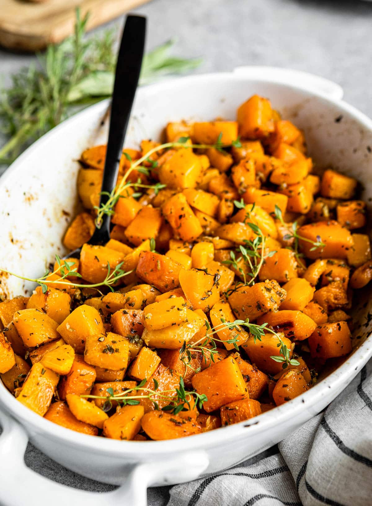 baking dish full of roasted cubed butternut squash baked with fresh herbs.