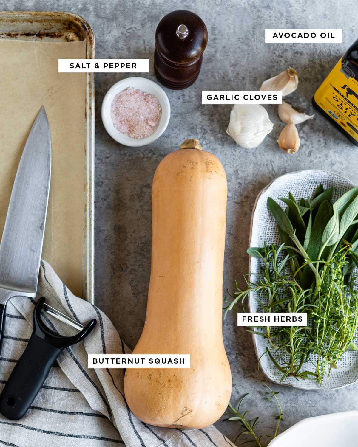 ingredients for roasting squash including avocado oil, salt, pepper, garlic cloves and fresh herbs.