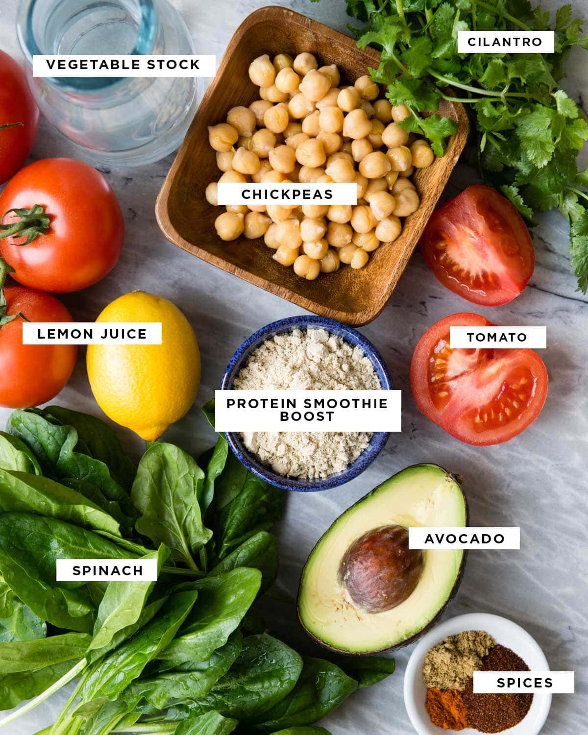 ingredients for a savory smoothie including cilantro, chickpeas, tomato, protein smoothie boost, avocado, spices, spinach, lemon juice and vegetable stock