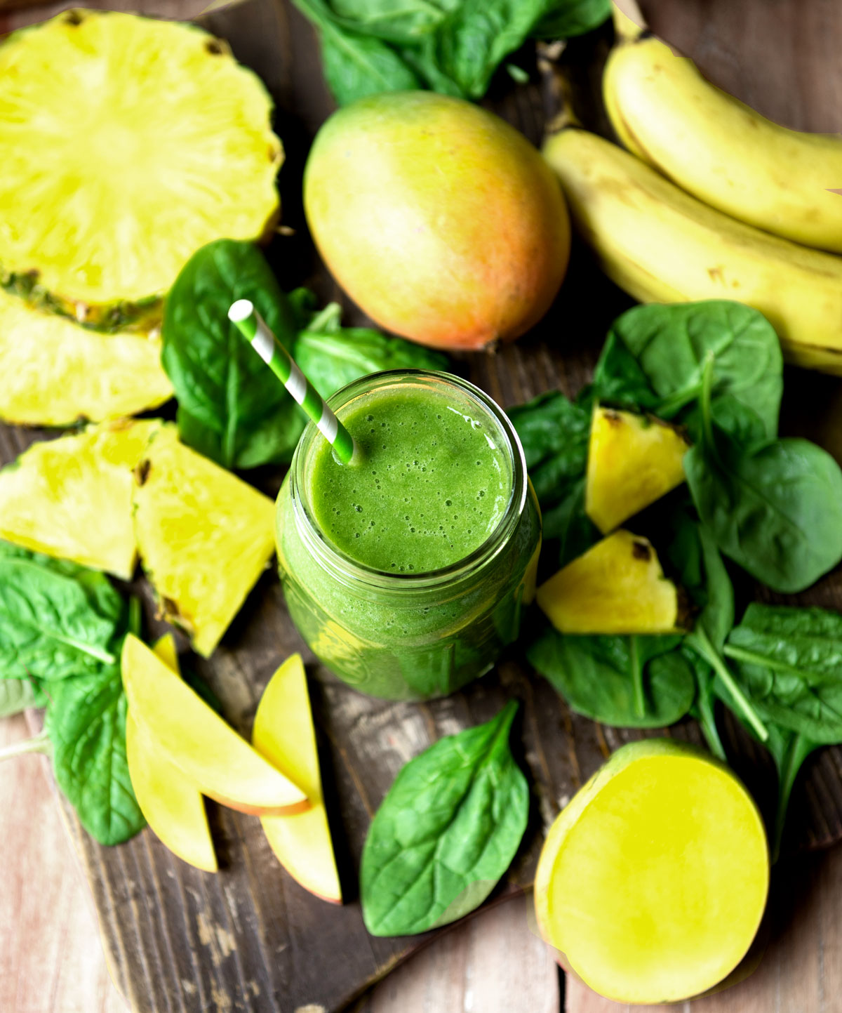 Best green smoothie recipe in a mason jar surrounded by fresh baby spinach leaves.