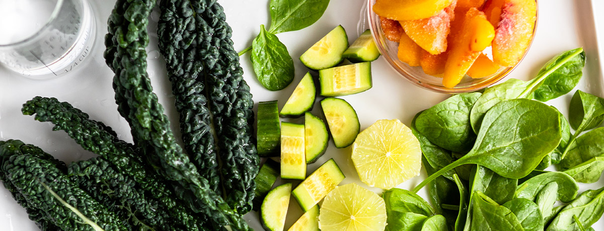 Fresh kale, spinach, lime and cucumbers on table to make a smoothie