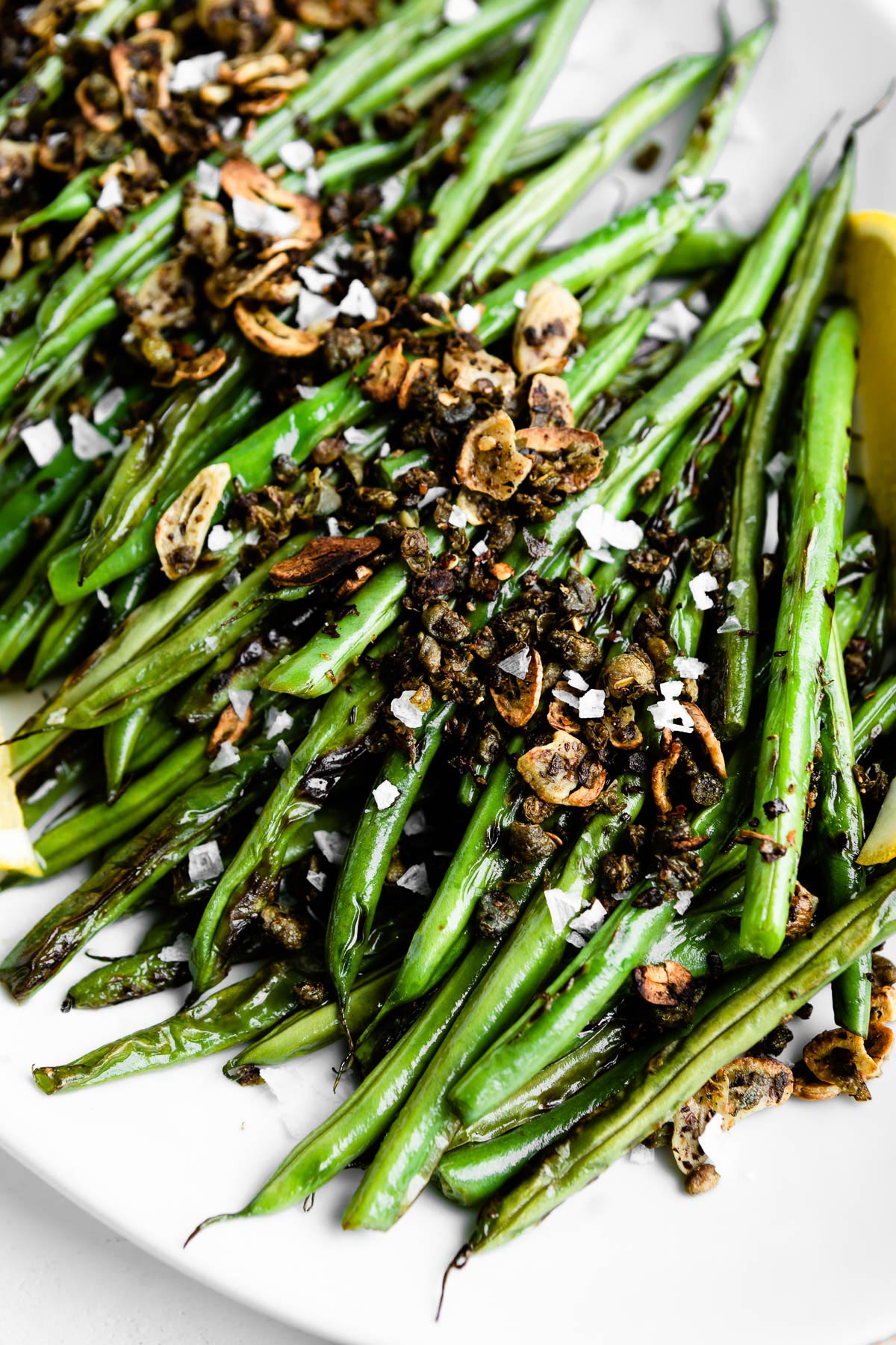 A close-up image detailing a skillet green bean side dish with fresh sautéed topping.