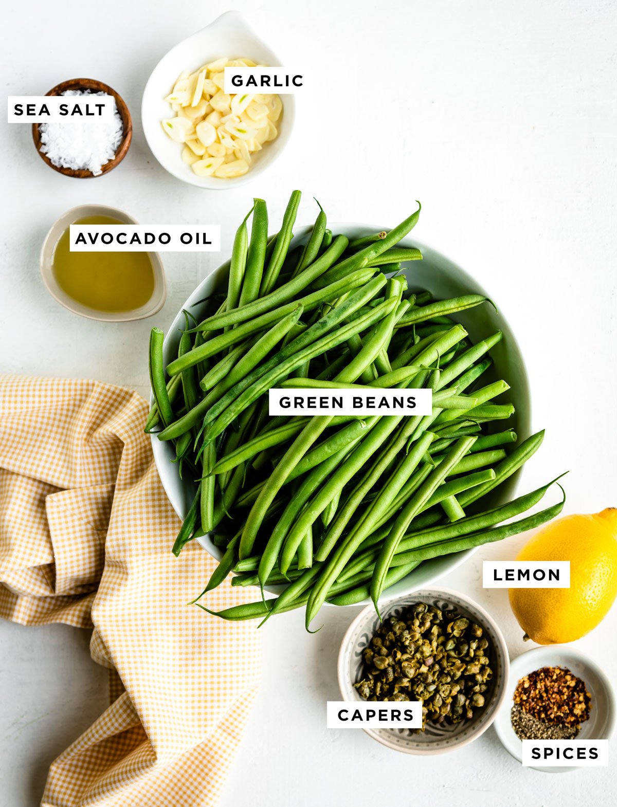 Labeled ingredients for skillet green beans, including sea salt, garlic, avocado oil, green beans, lemon, capers, and spices.