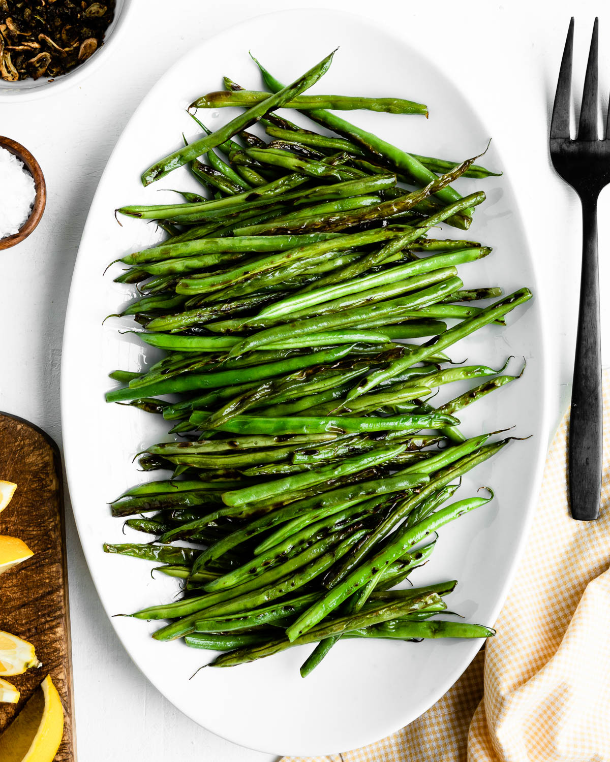 white serving plate toped with blackened green beans.