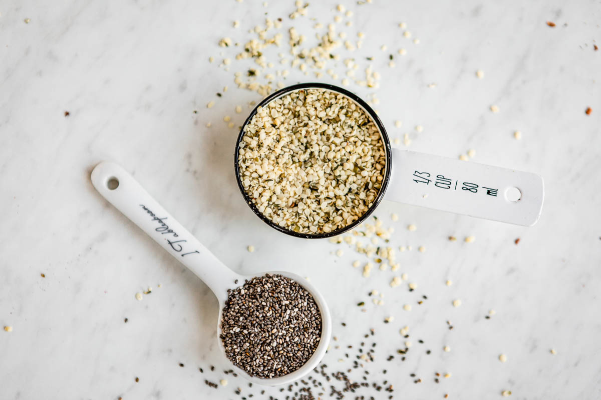 1/3 cup of hemp hearts and 1 tablespoon of chia seeds both in white measuring spoons.