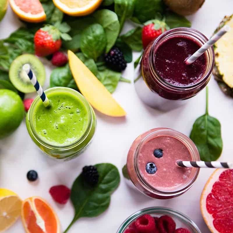 Colorful smoothies with fresh fruits and leafy greens for healthy living.