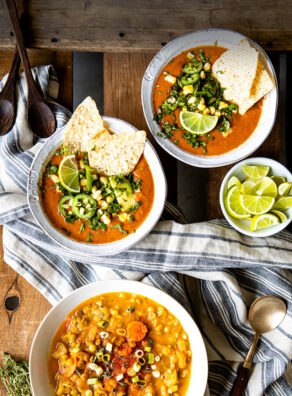 Several bowls of soup on a table with a cloth napkin.