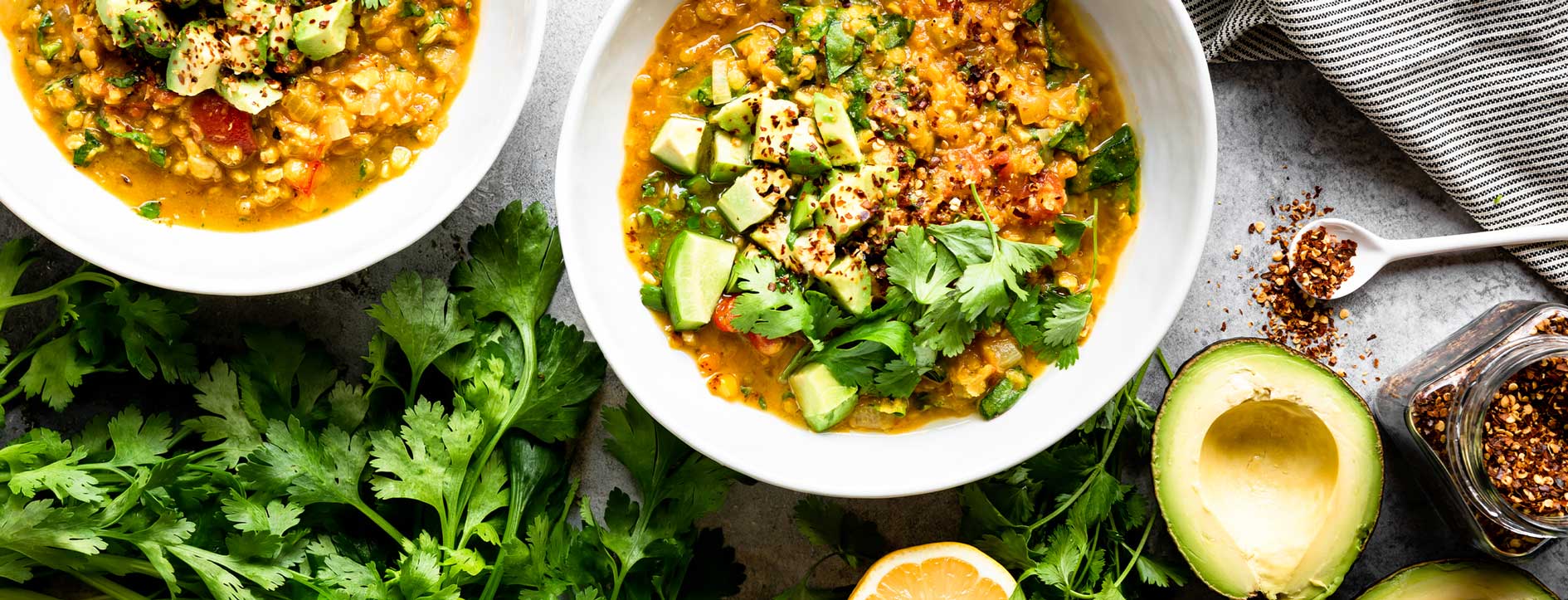 Healthy vegetable lentil soup with avocado and cilantro garnishes.