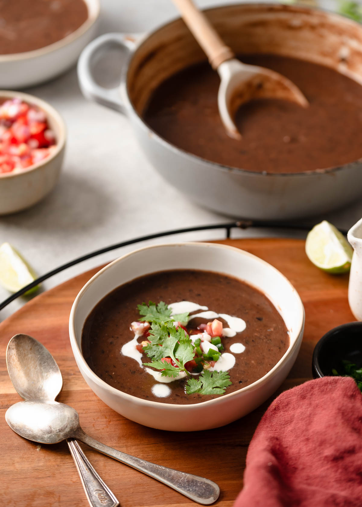 A single serving of spicy black bean soup with vegan sour cream, fresh salsa, and cilantro.