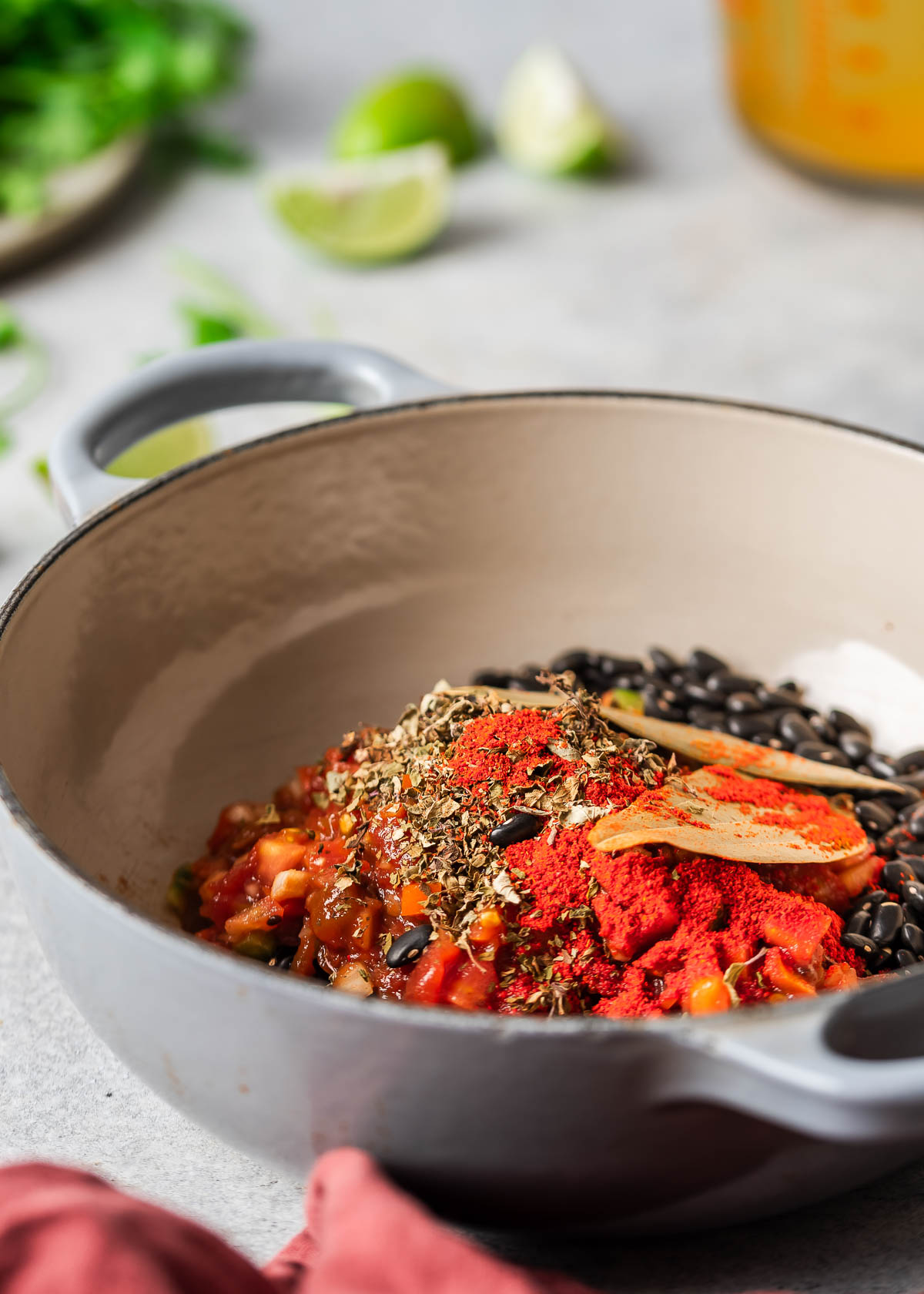 Dried black beans, herbs and spices prepared in a gray pot.