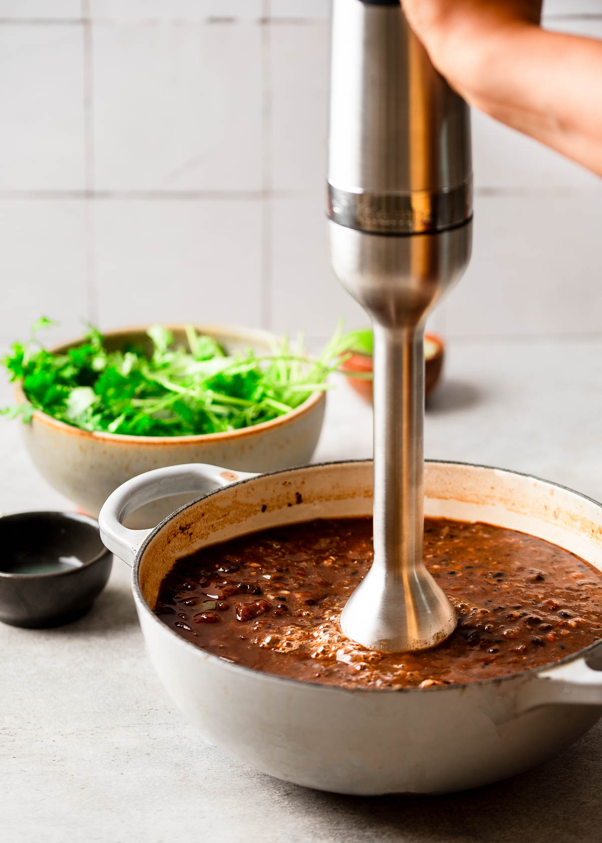 An immersion blender pureeing spicy black bean soup.