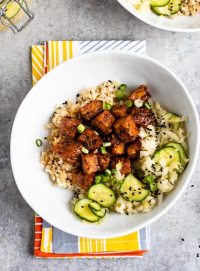 white bowl of spicy marinated tempeh on a colorful napkin.