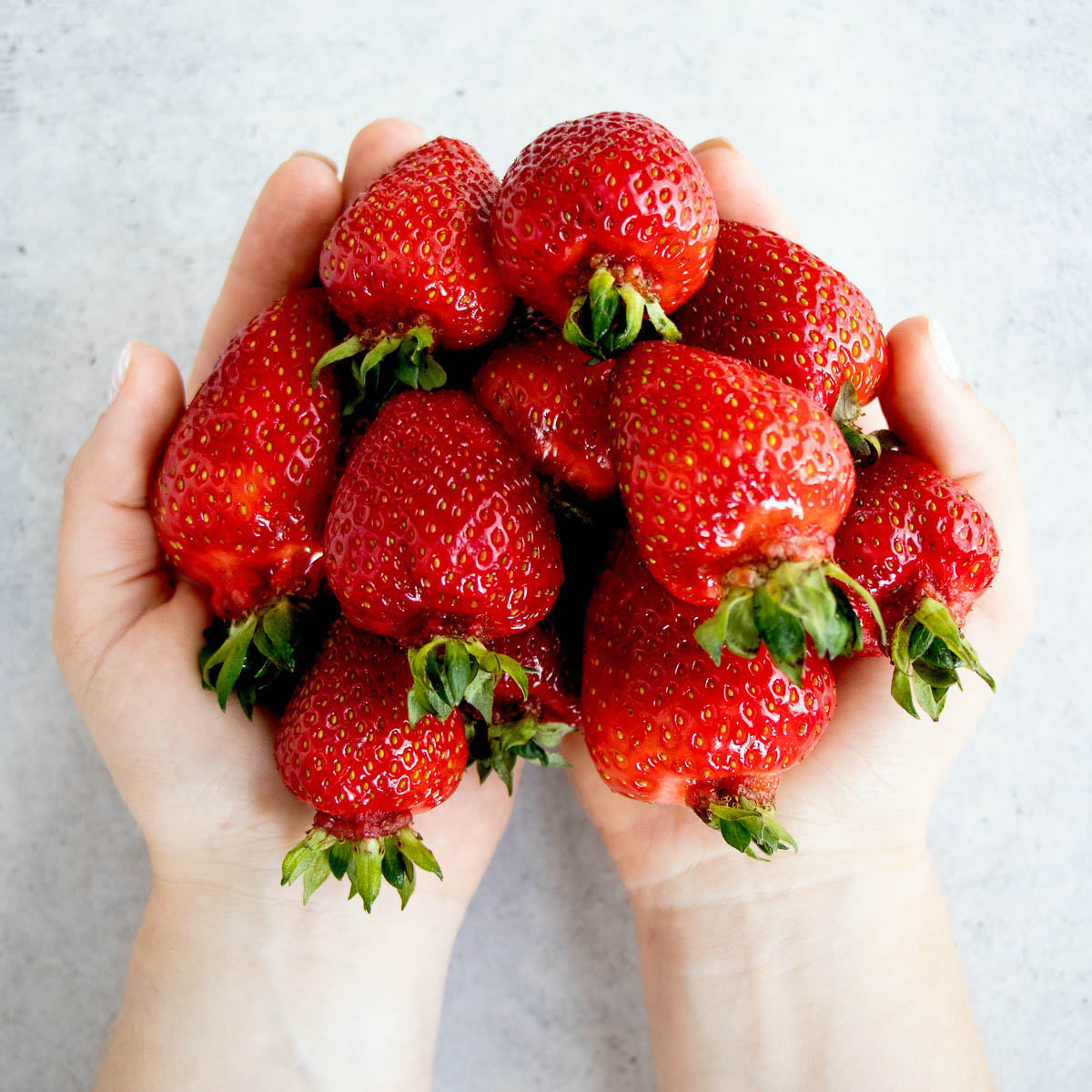 Hands full of whole strawberries