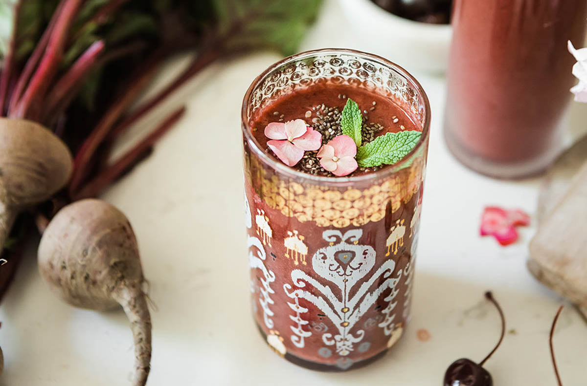berry beet smoothie topped with flowers, mint and chia seeds for a spring meals breakfast