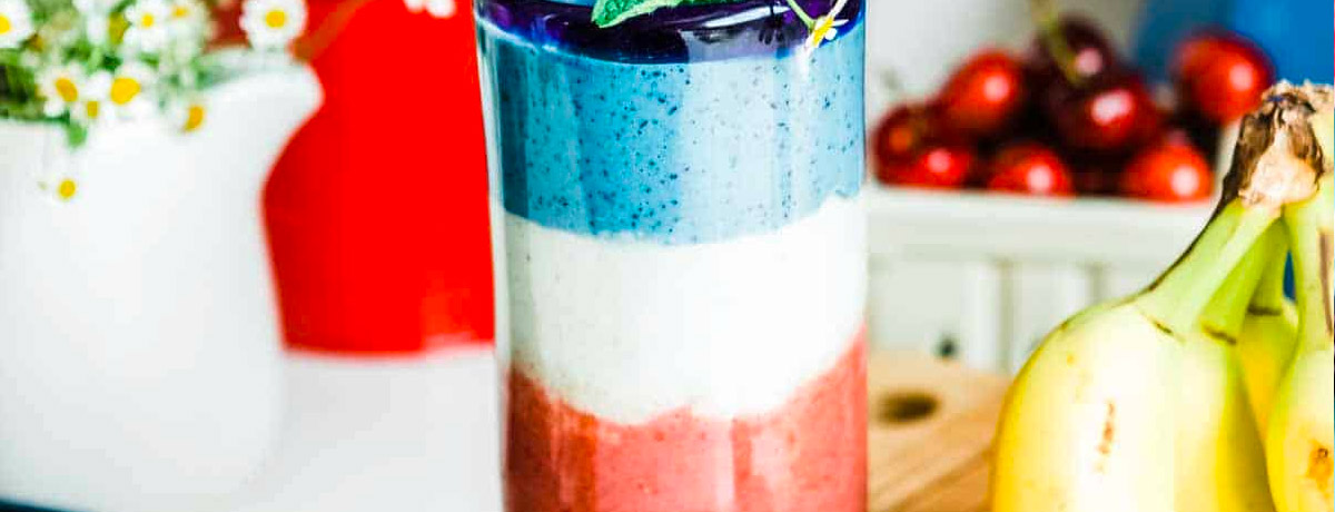 layered smoothie in clear jar; top layer is blue, middle layer is white, bottom layer is red