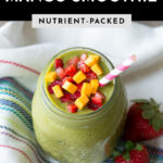 Strawberry mango smoothie in glass jar with paper straw and topped with fresh fruit.