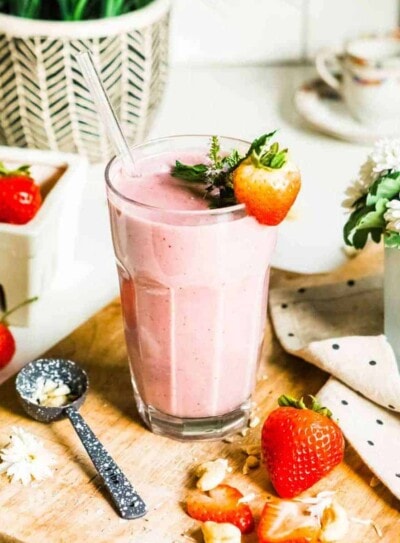 strawberry smoothie in glass with fresh strawberry as garnish.