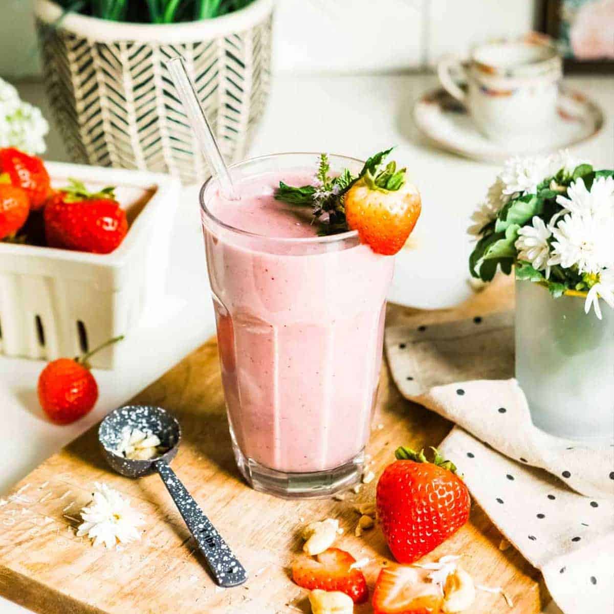 strawberry smoothie in glass with fresh strawberry as garnish.