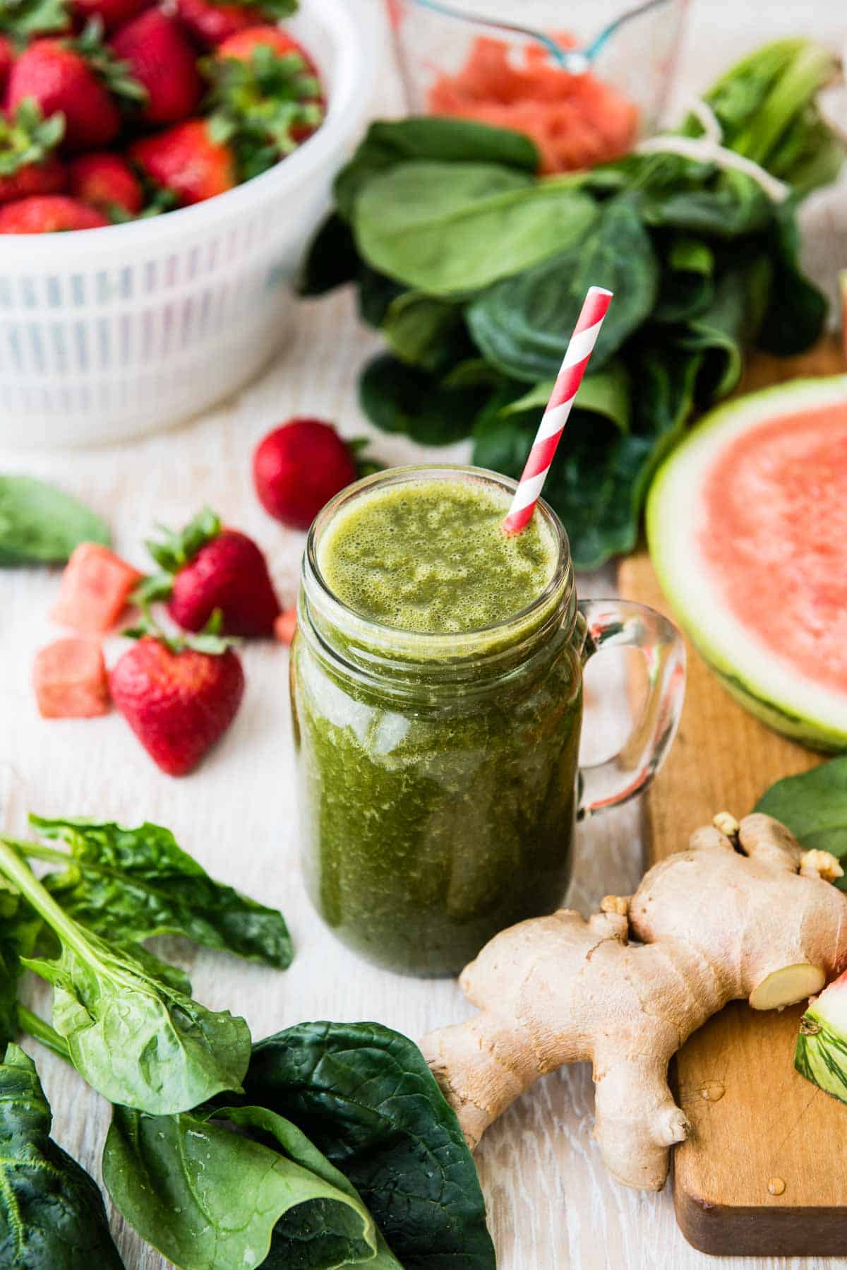 strawberry watermelon green smoothie in a glass mug with a paper straw.