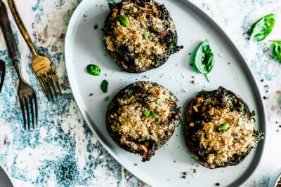 Stuffed portobello mushrooms on plate with fresh basil.