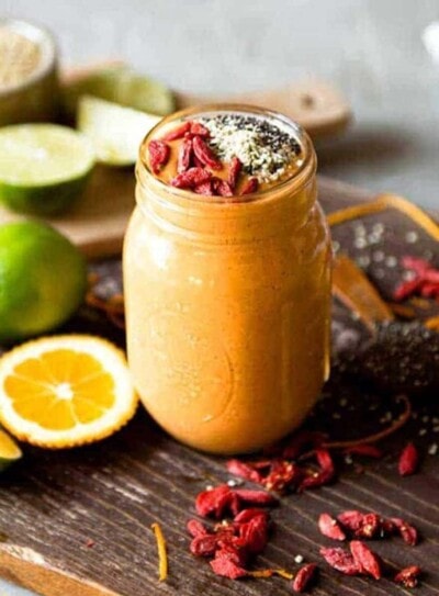 orange superfood smoothie in a glass mug topped with goji berries and hemp hearts.