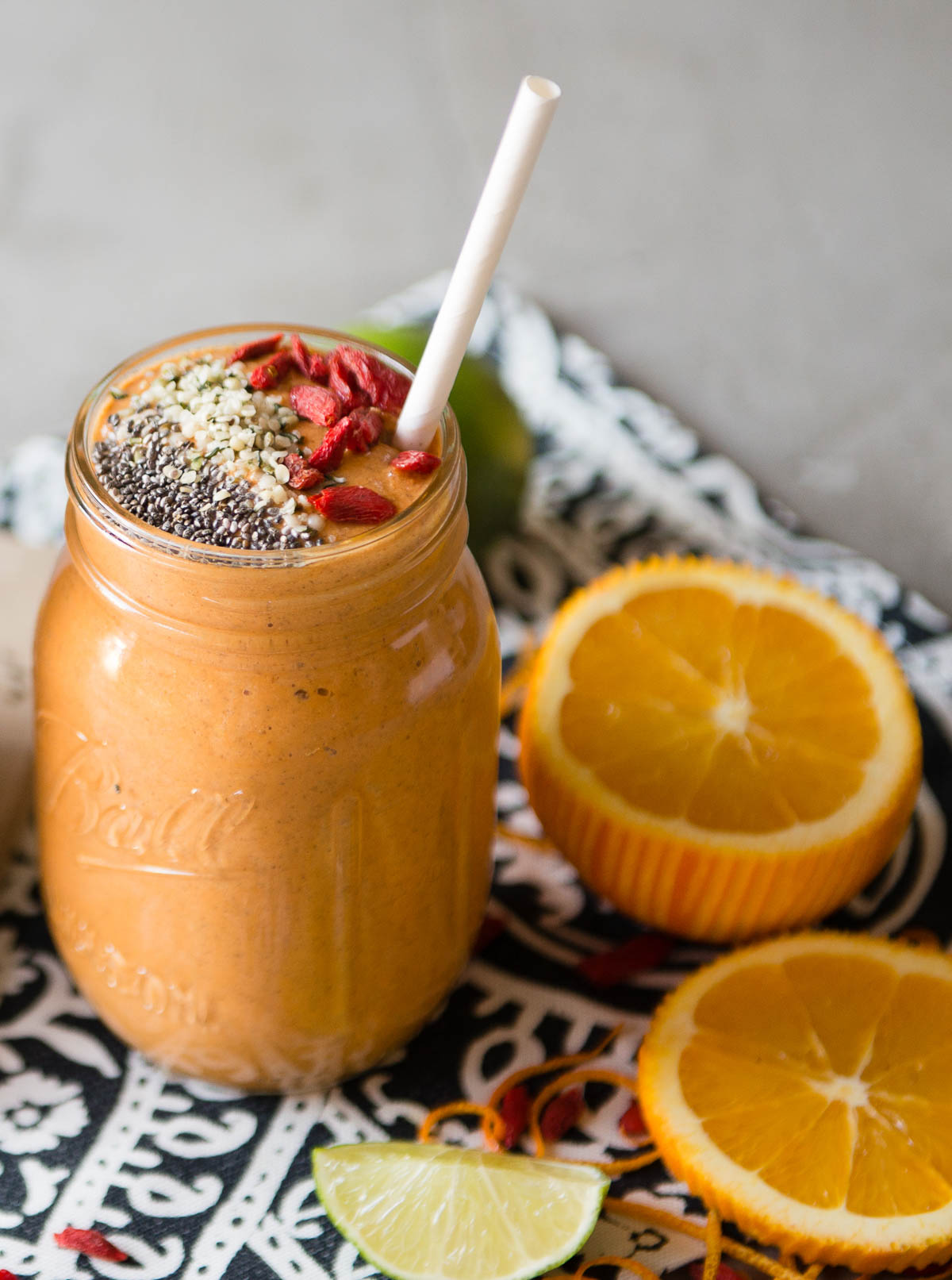 orange smoothie in a glass jar next to an open orange.