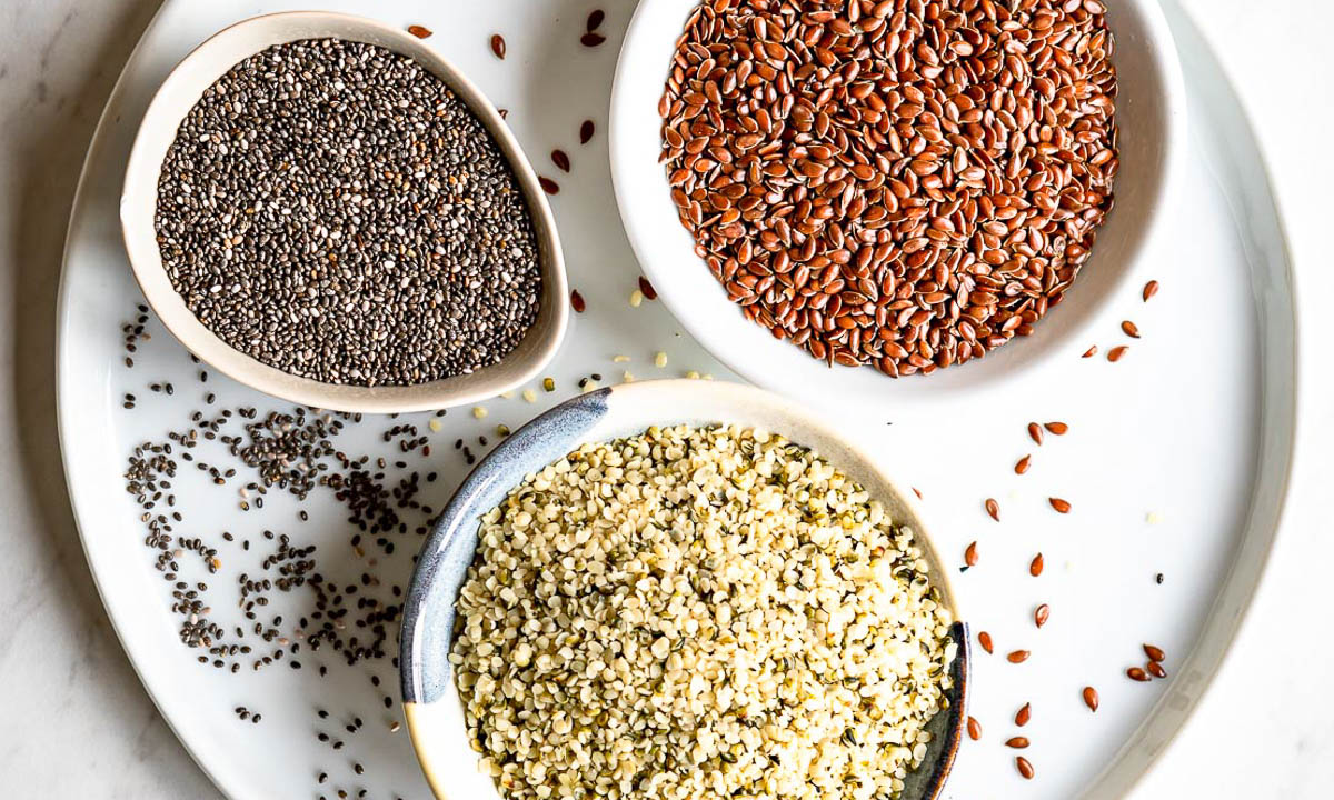 white tray with 3 bowls of chia seeds, hemp hearts and flaxseed.