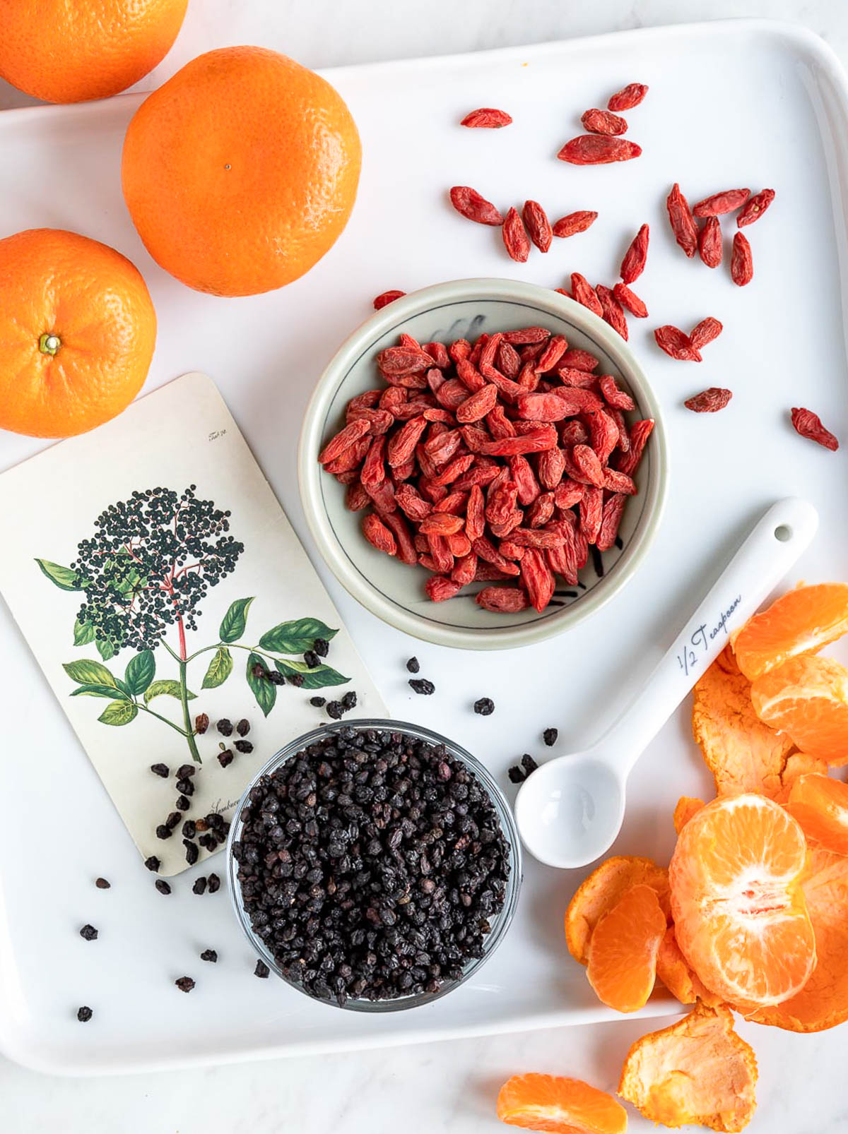 superfoods that help boost immunity including goji berries, oranges and elderberry in white bowls.