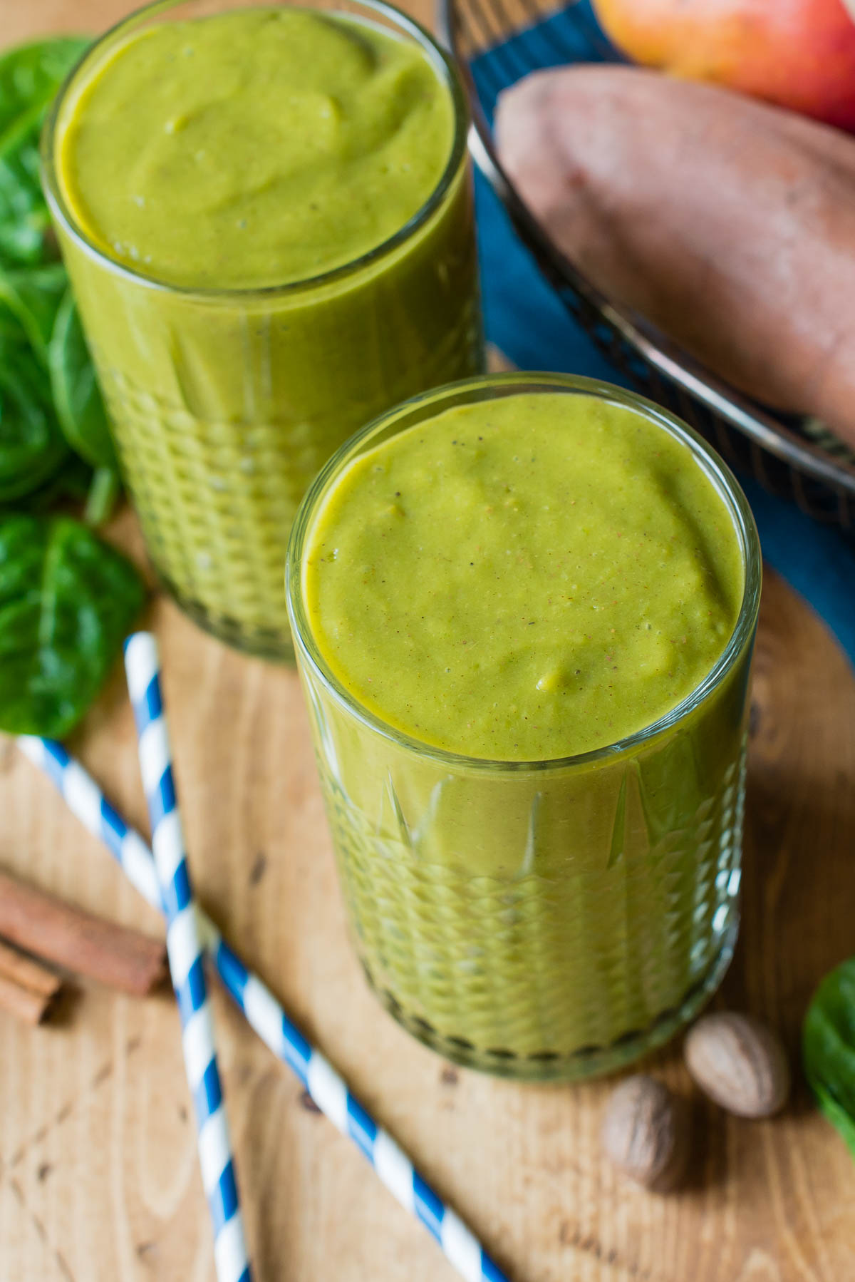 Two sweet potato smoothies with striped straws on the table. 