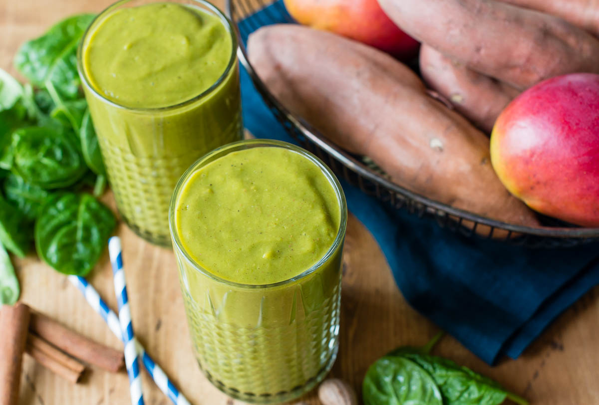 Two sweet potato smoothies in glasses on a rustic wooden table.