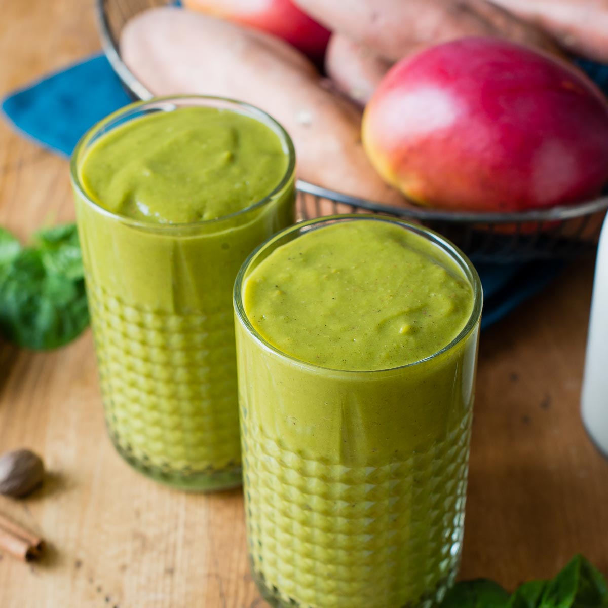 Two glasses of sweet potato smoothie on a table with fresh ingredients.