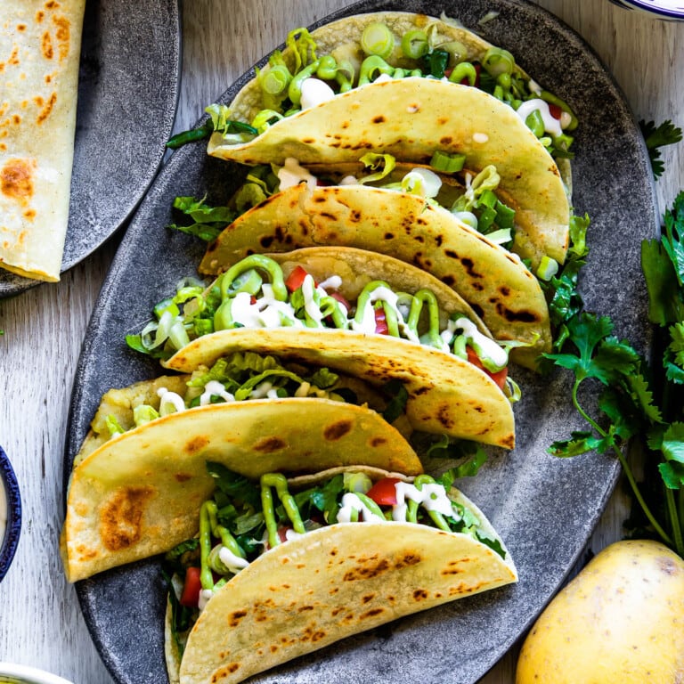 5 Tacos de papa or crispy potato tacos on an oval, gray plate.