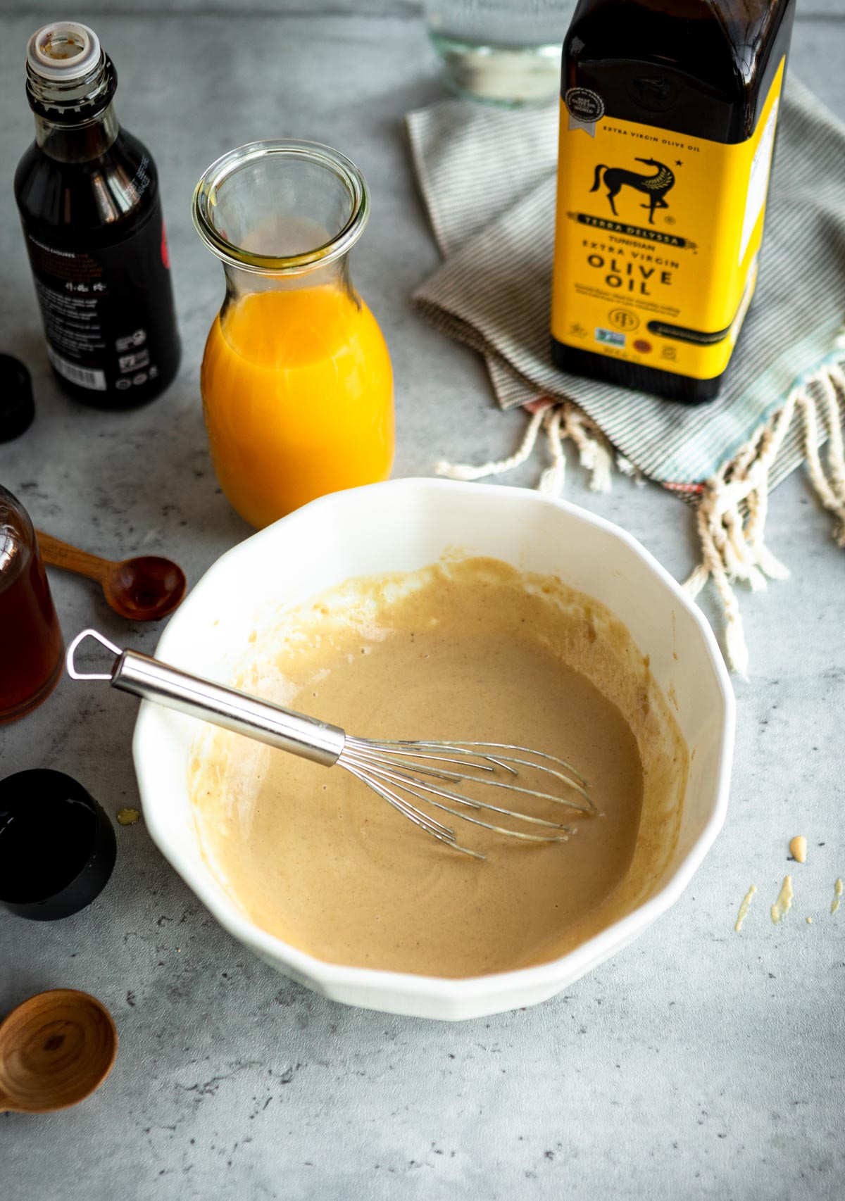 whisking tahini salad dressing recipe in a white bowl.