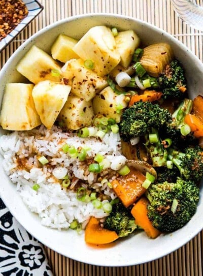teriyaki rice bowl with pineapple, broccoli and carrots in a white bowl.