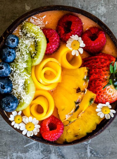 tropical smoothie bowl topped with fresh fruit.