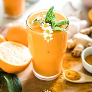 Tall glass of peach-colored honey turmeric smoothie.